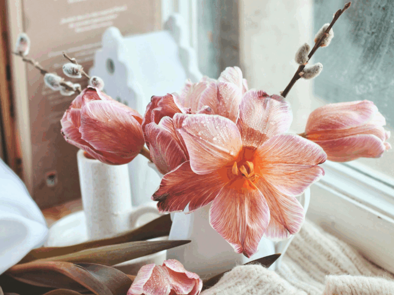 Green indoor plant in a white decorative pot on a white windowsill with a soft blurred background.