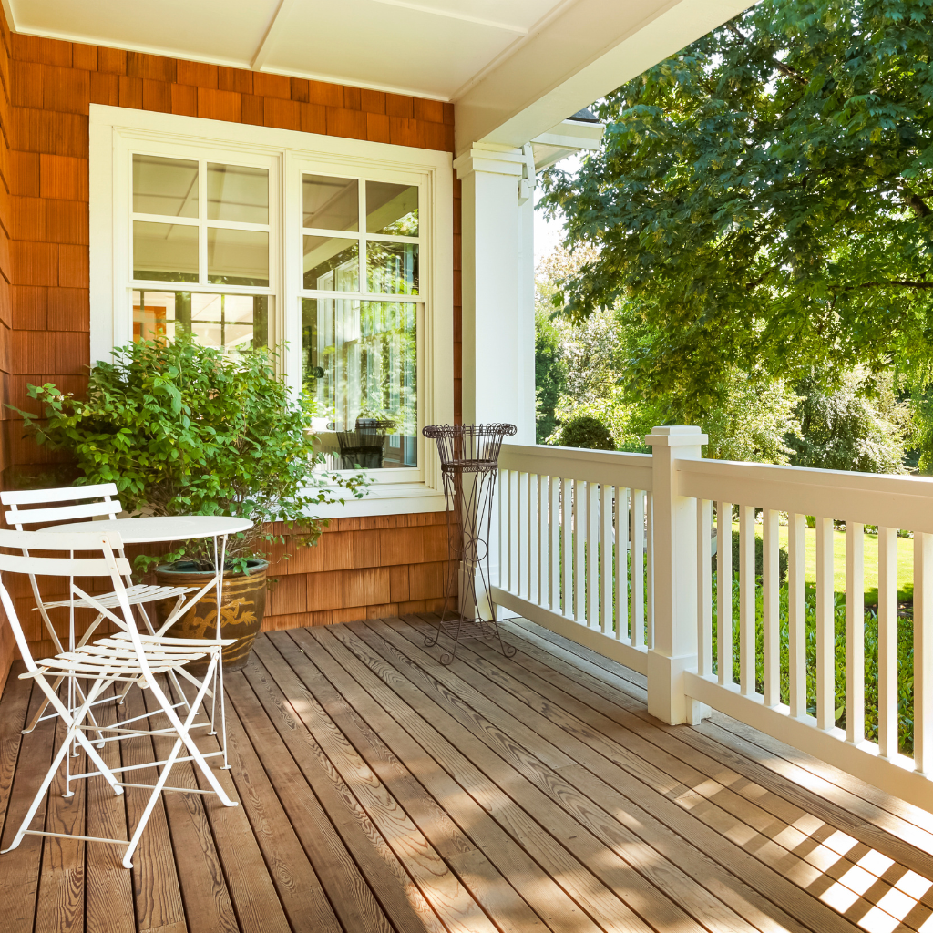 Wooden porch with white metal bistro set and a green potted plant