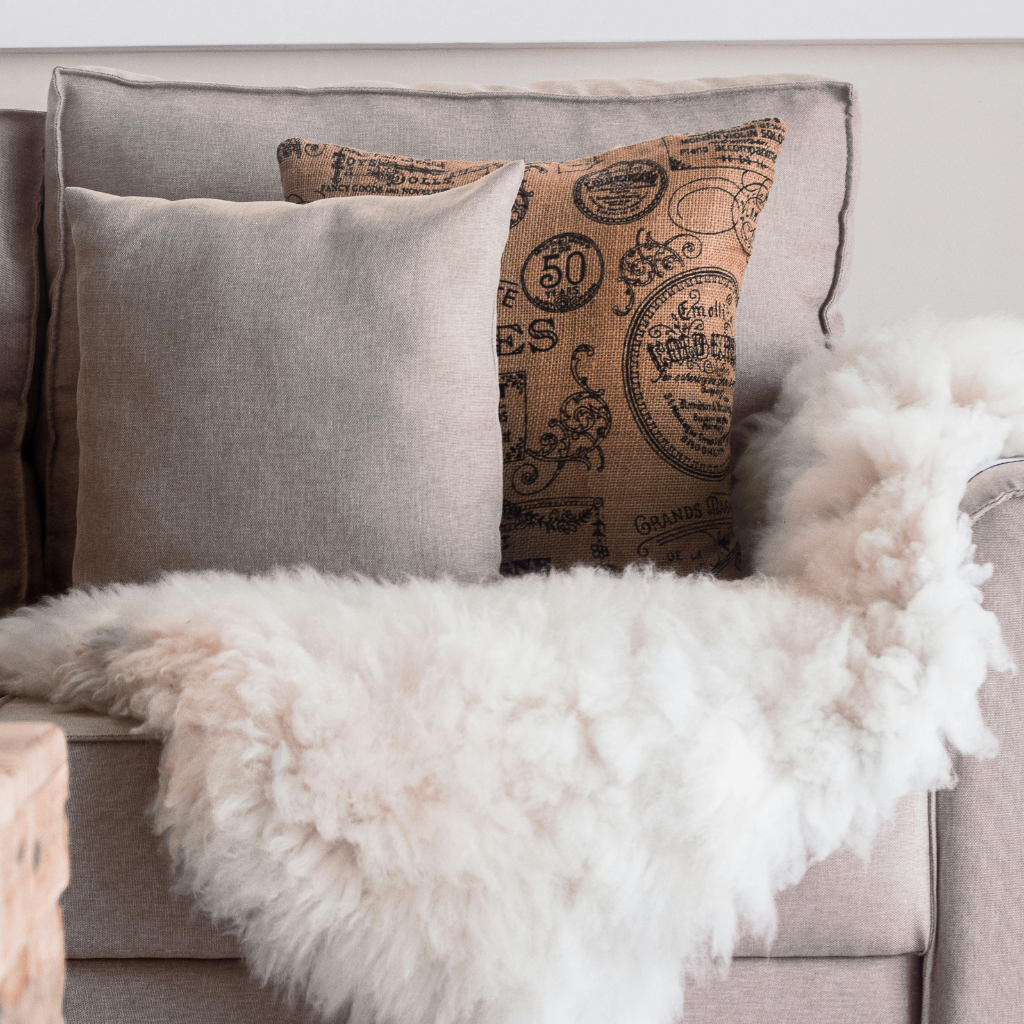 Neutral-toned throw pillows and fluffy white blanket on a beige couch