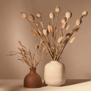 Minimalist dried flower arrangements in neutral ceramic vases on a beige background