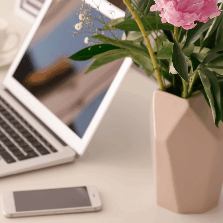 Modern workspace with laptop, flowers, and smartphone