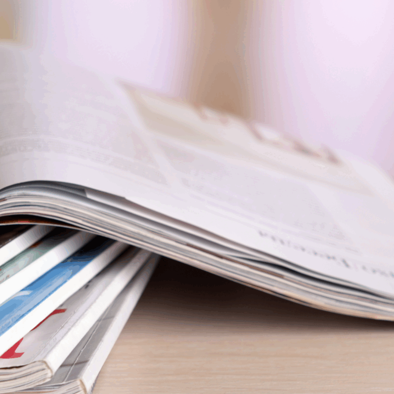 Stack of open magazines on a light wooden table
