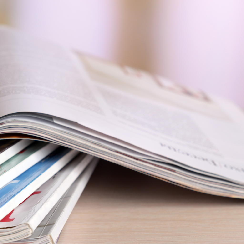Stack of open magazines on a light wooden table