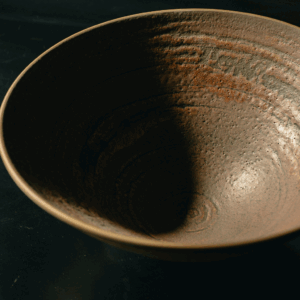 Handcrafted dark brown ceramic bowl with textured swirl interior