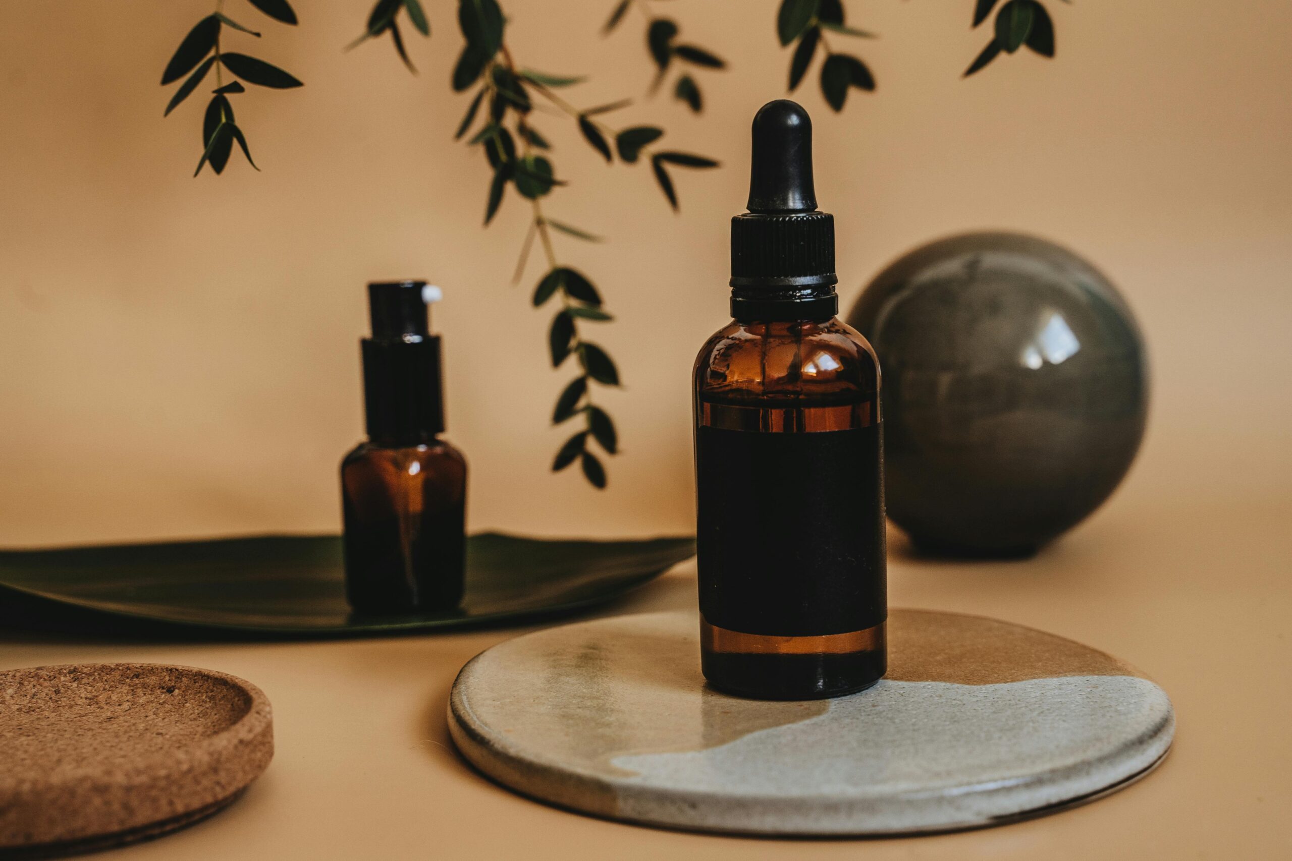 Amber glass dropper bottle and pump bottle displayed on ceramic and cork trays