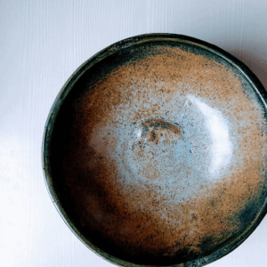 Top view of a blue and rust-toned ceramic plate with a speckled finish