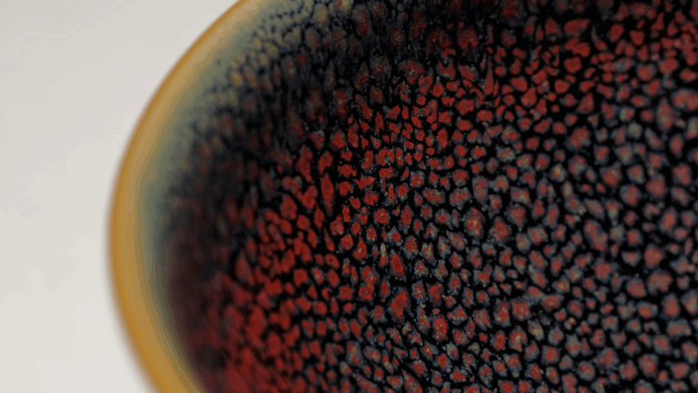 Macro shot of red and black textured ceramic glaze on pottery