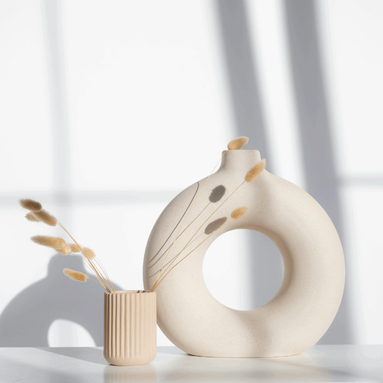 A tall feather, reed, or dried branch arrangement in a narrow vase