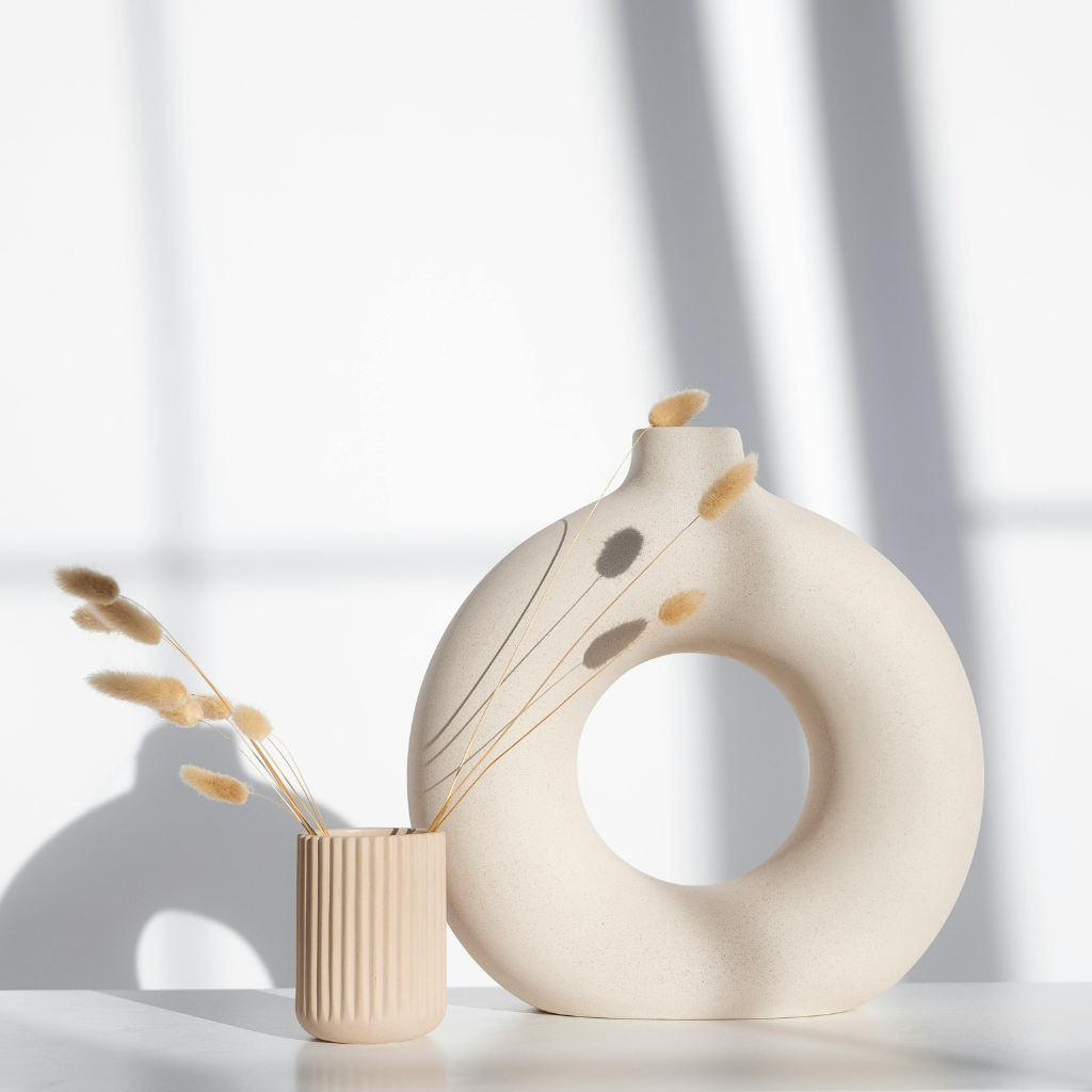 A tall feather, reed, or dried branch arrangement in a narrow vase