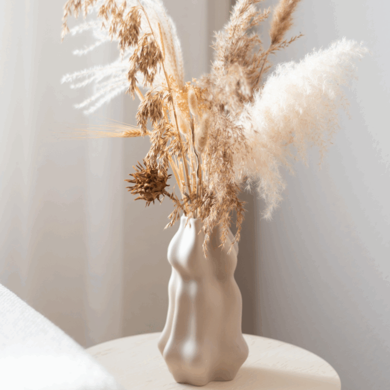 Sculptural ceramic vase with dried pampas grass and textured florals in a minimalist setting