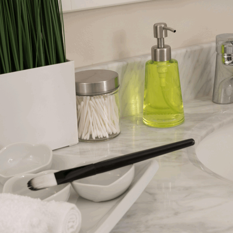 Marble bathroom countertop styled with cotton swabs, soap dispenser, and small ceramic bowls
