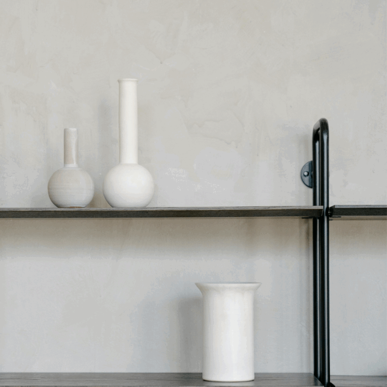 Set of minimalist white ceramic vases displayed on black wall-mounted shelves