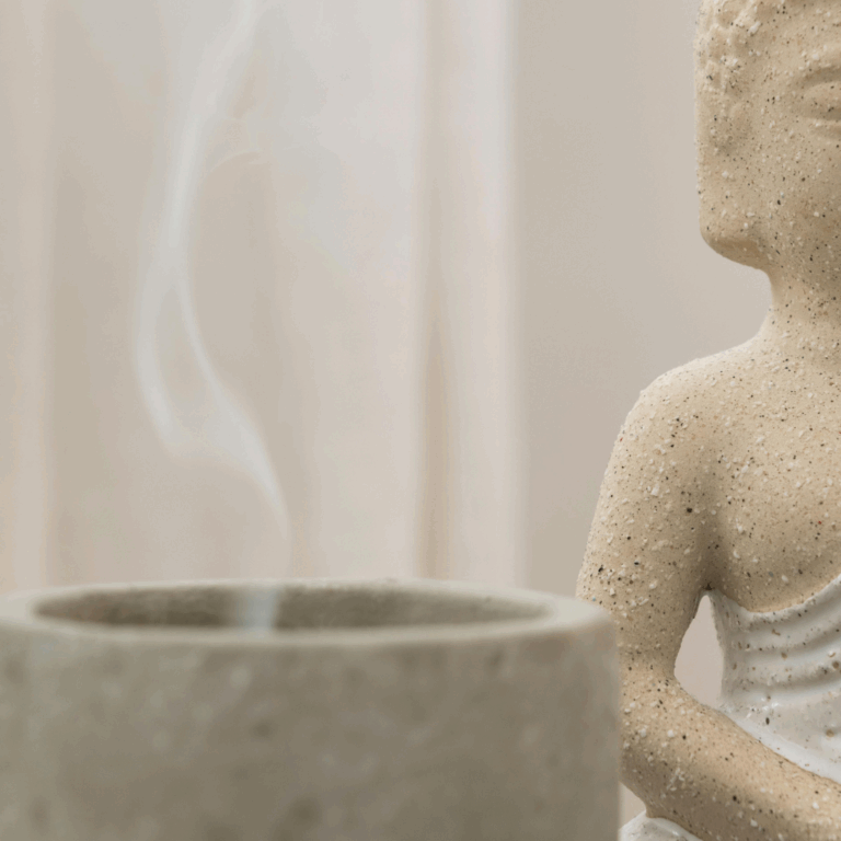Ceramic Buddha statue with incense smoke in a minimalist neutral home setting