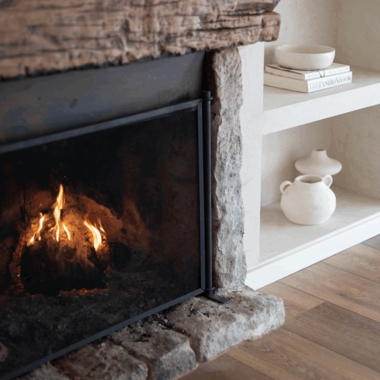 Rustic stone fireplace with white ceramic vases and bowls styled on adjacent built-in shelves