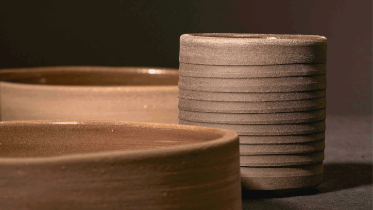 Close-up of handcrafted textured brown ceramic bowls and cup in a minimalist setting