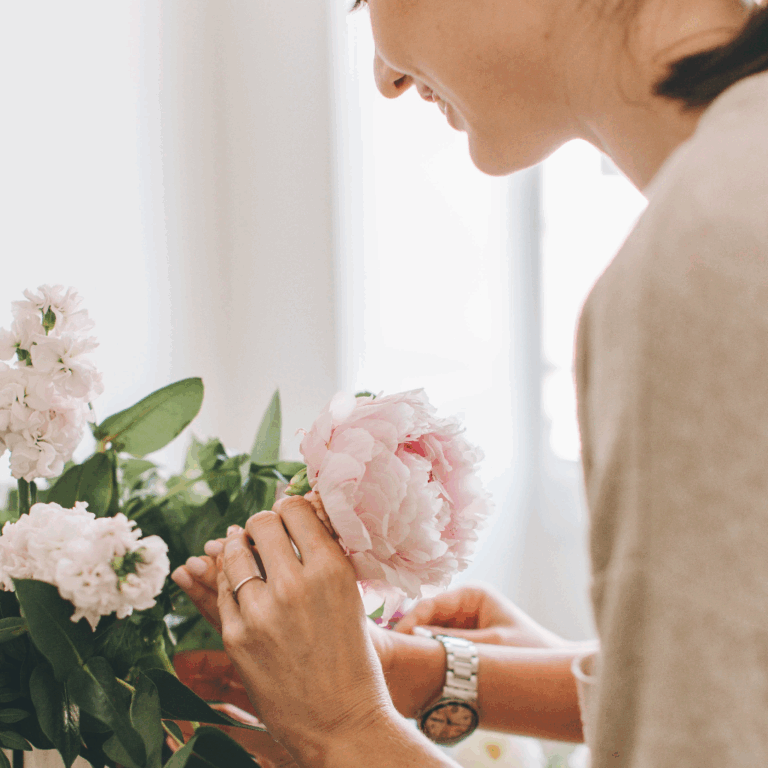 Woman arranging soft pink peonies in a vase