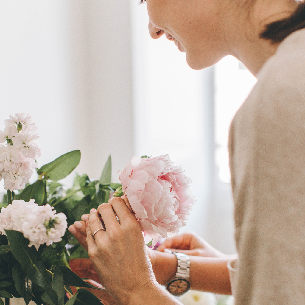 Woman arranging soft pink peonies in a vase