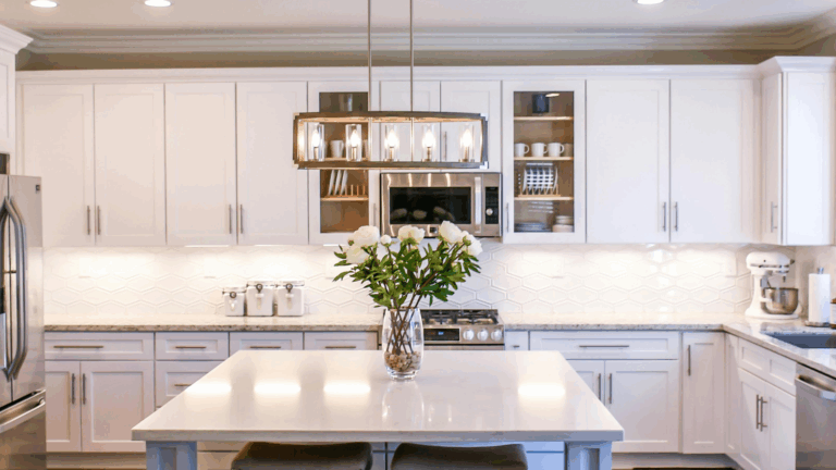 Bright white kitchen with flower arrangement on island and modern lighting fixture