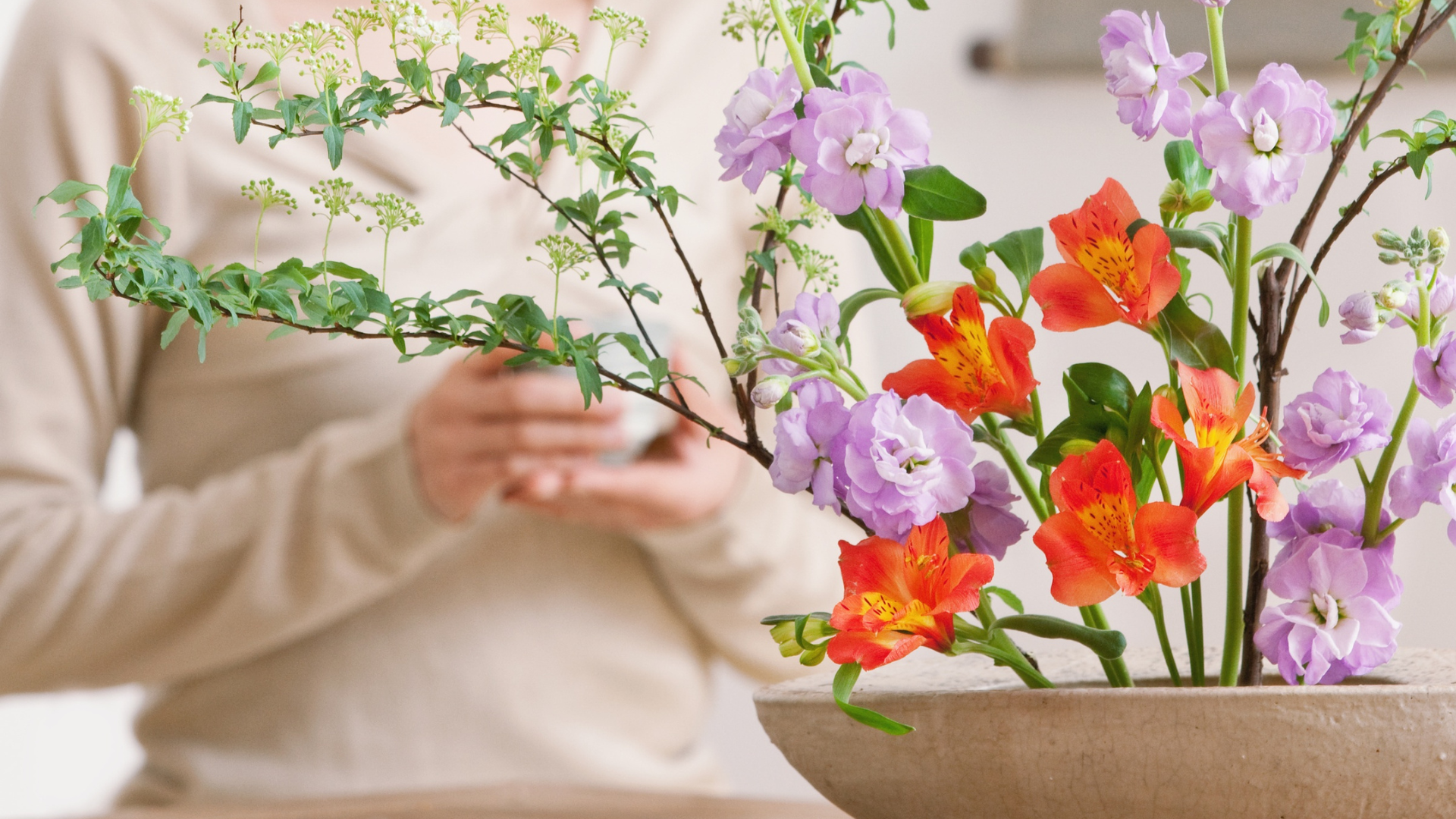 Vibrant flower arrangement with red and purple blooms in a ceramic bowl