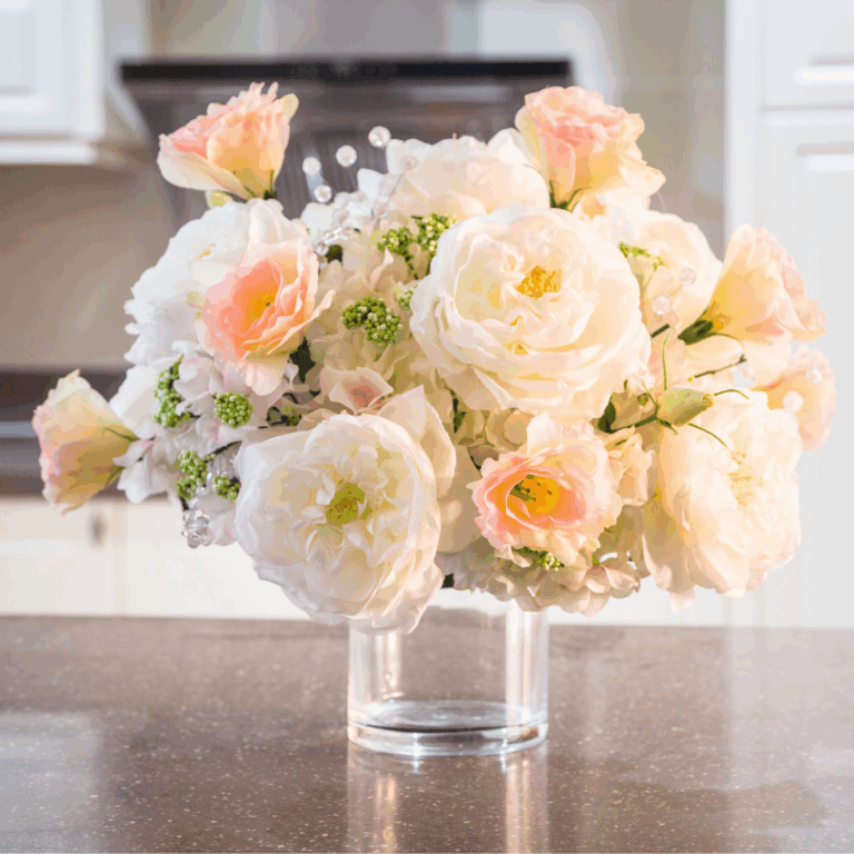 Soft pink and white roses in a clear glass vase on a kitchen counter