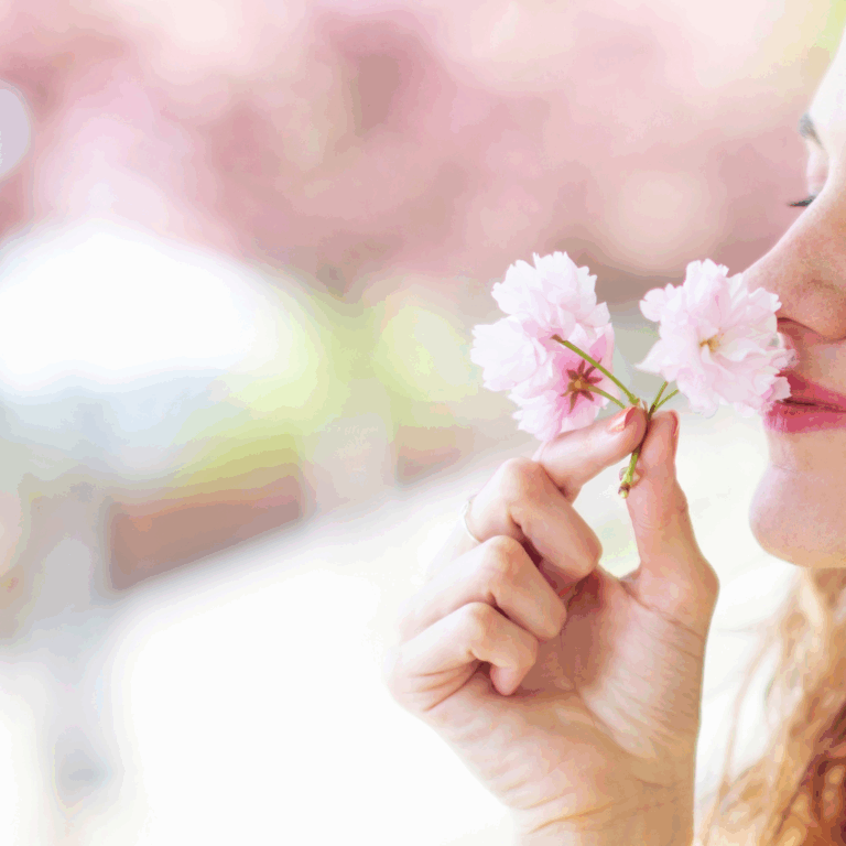 Woman smelling cherry blossom flowers with a soft expression