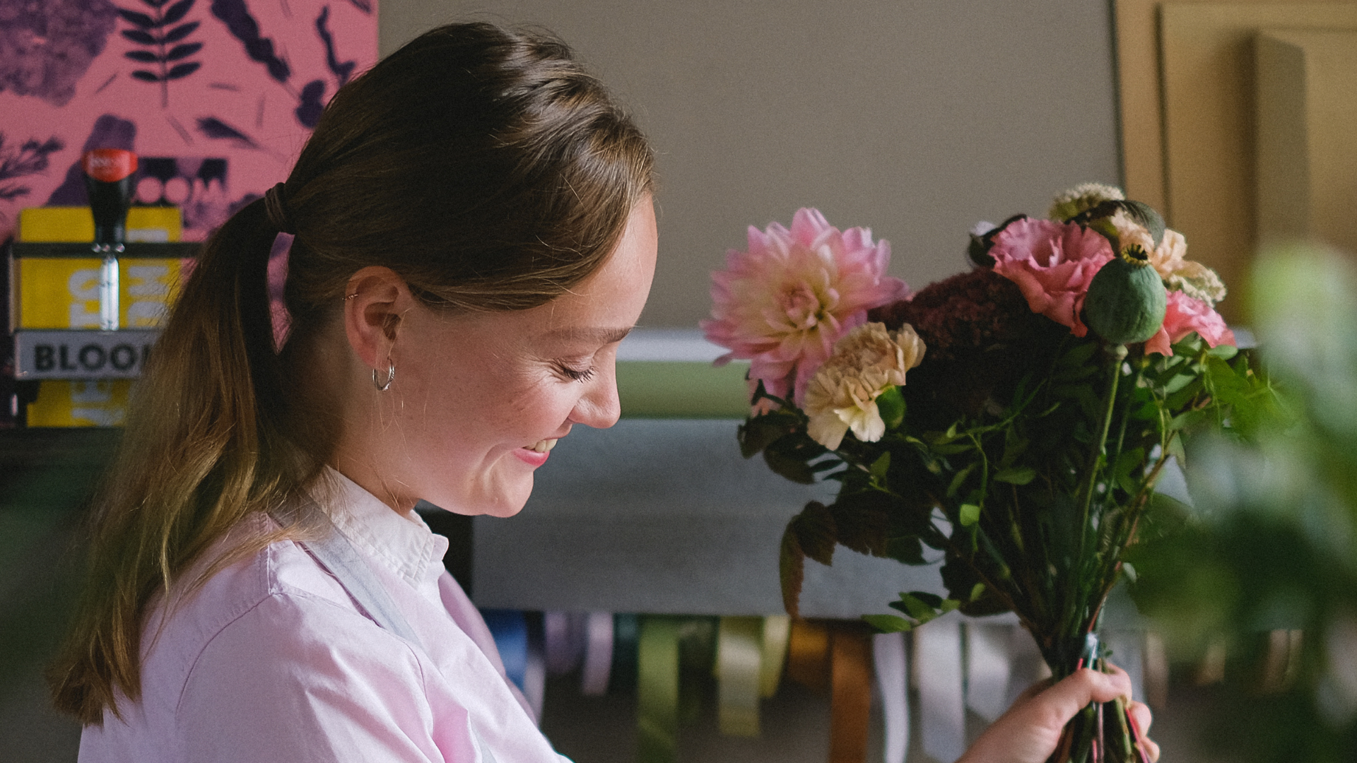 Woman smiling while arranging a bouquet of fresh pink and cream flowers