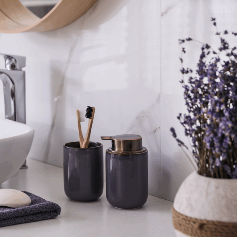 Lavender stems in a vase beside black ceramic soap dispensers in a bathroom