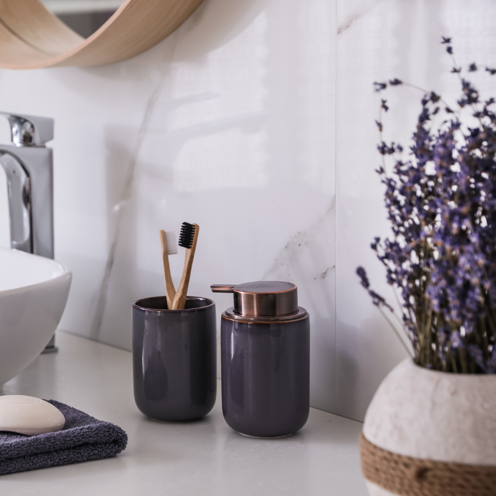 Lavender stems in a vase beside black ceramic soap dispensers in a bathroom