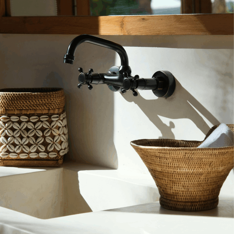 Black wall-mounted faucet above a minimalist sink with decorative woven baskets, evoking natural, spa-like style.