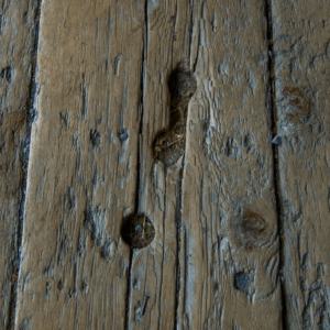 Close-up of a damaged, aged wooden floor with holes and cracks.