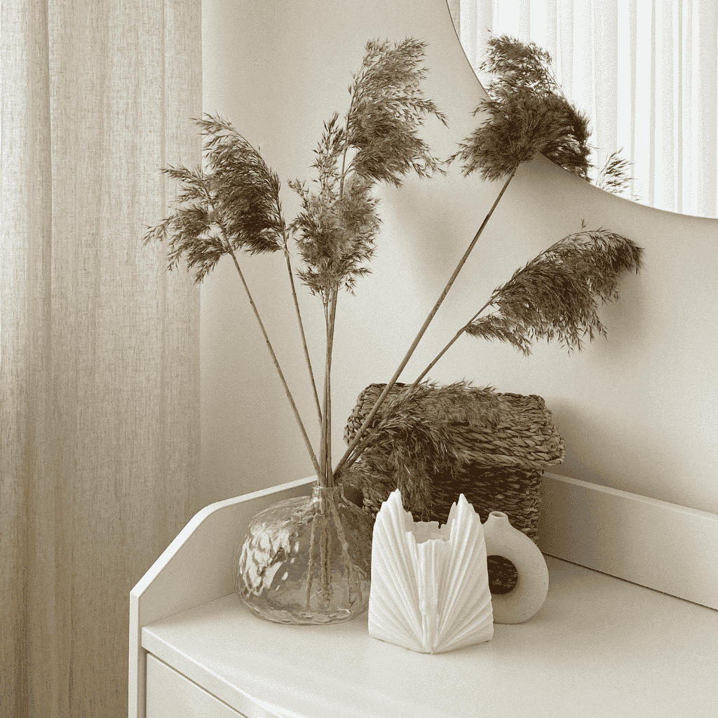 Pampas grass in a glass vase with neutral home decor accents.