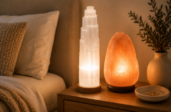 White selenite tower lamp and pink Himalayan salt lamp glowing side-by-side on a wood nightstand in a calm bedroom.
