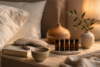Wood-grain diffuser misting beside five essential oil bottles on a marble tray in a calm bedtime bedroom.