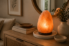 Himalayan salt lamp on a marble tray to prevent sweating, glowing on a wood console with a vase and books.